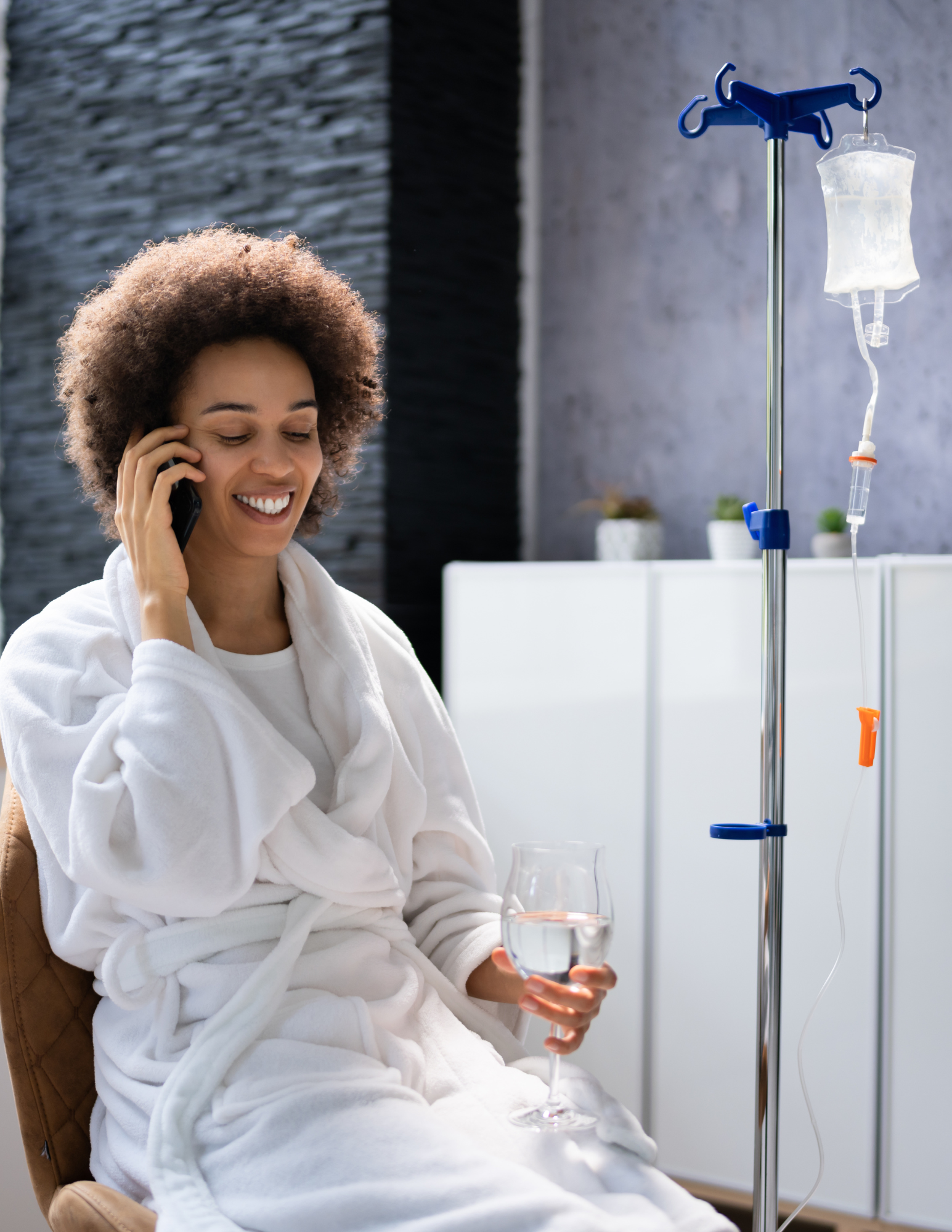 lady smiling and speaking on the phone while receiving IV therapy